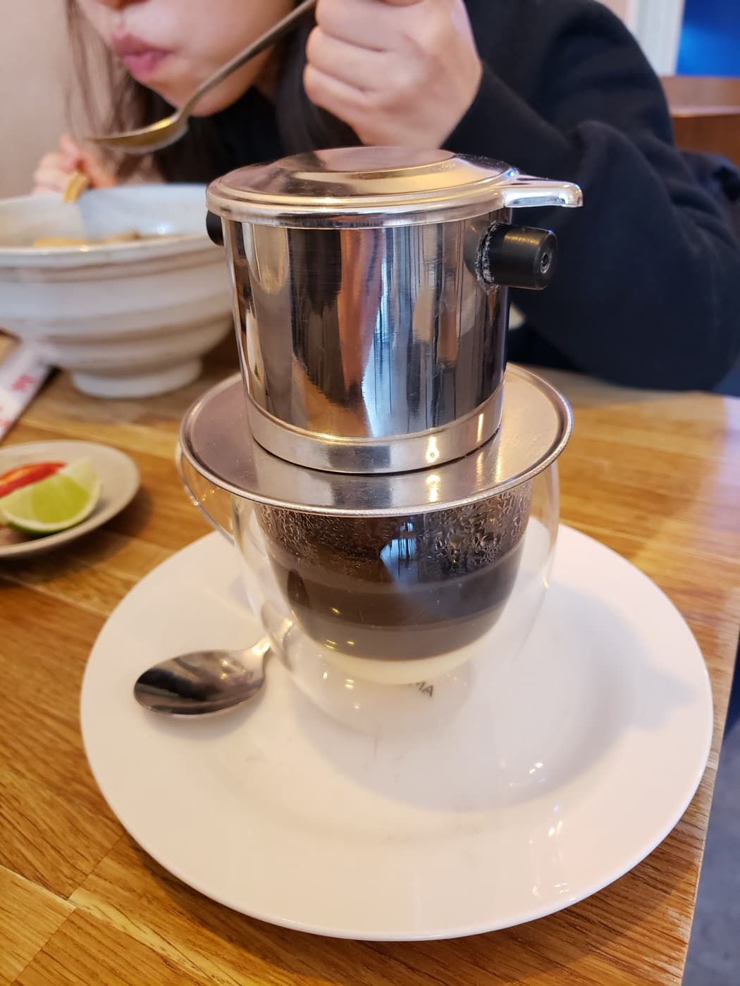 Phin cà phê nhỏ giọt vào ly trên nền gỗ ấm